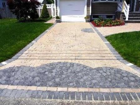 A brick driveway leading to a house with a white garage door