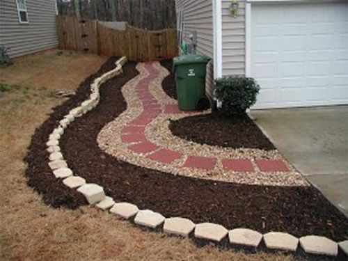 A walkway leading to a garage with a green trash can in the background.