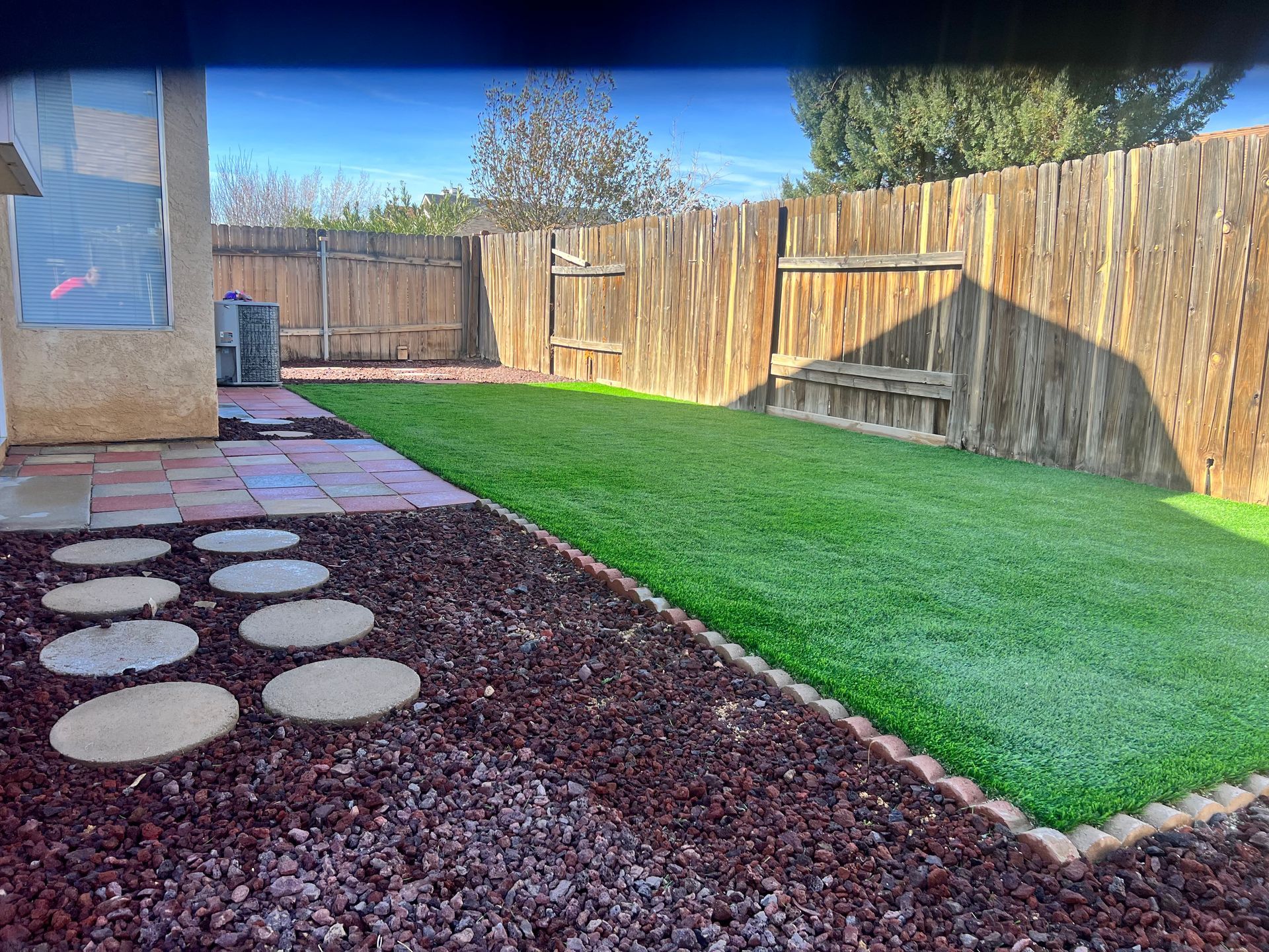 A backyard with a wooden fence and a lush green lawn.