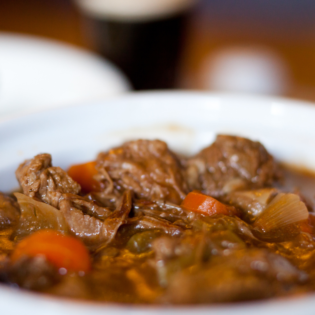 A close up of a bowl of stew with meat and carrots