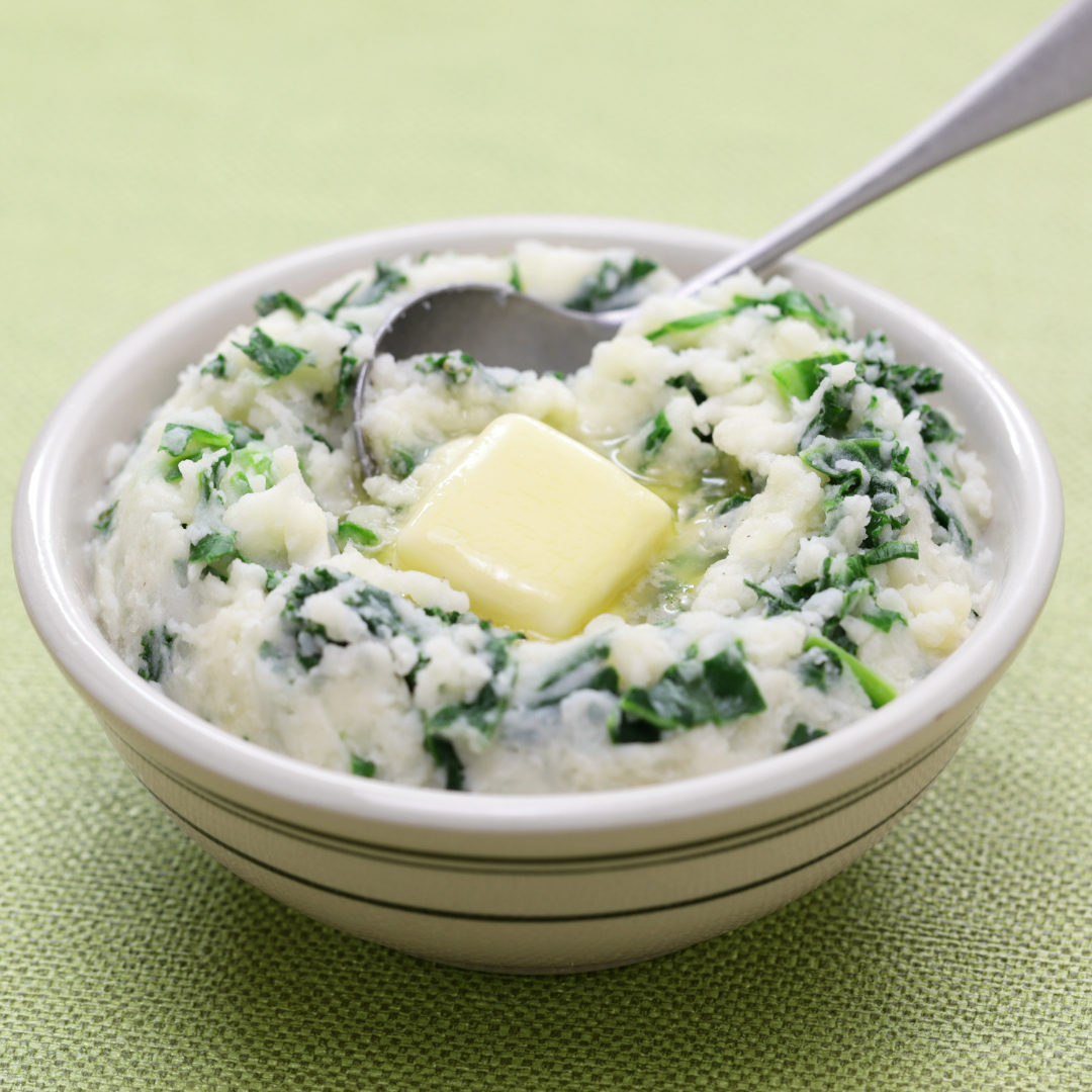 A bowl of mashed potatoes with butter and a spoon