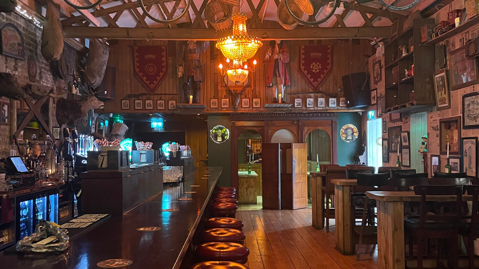 The inside of a bar with a long bar and stools.