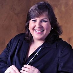 A woman in a black shirt is holding a pen and smiling.