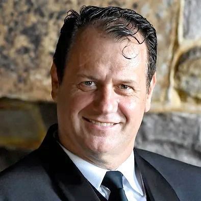 A man in a suit and tie is smiling for the camera.