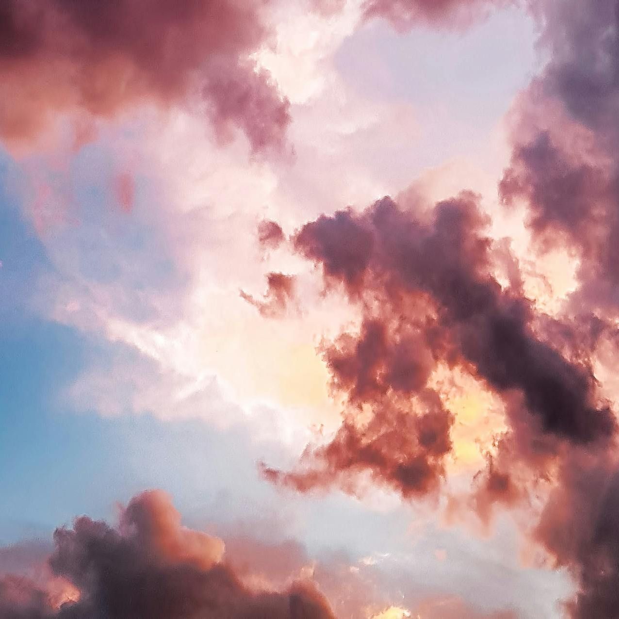 The sun is shining through the clouds in the sky at sunset.