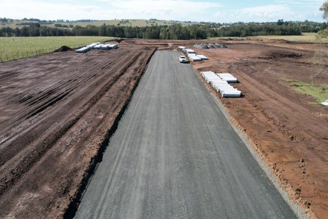 Gravel Road Under Construction, Brown Dirt Surrounds, Concrete Slabs, Green Field Background — Earthmoving in Maitland, NSW