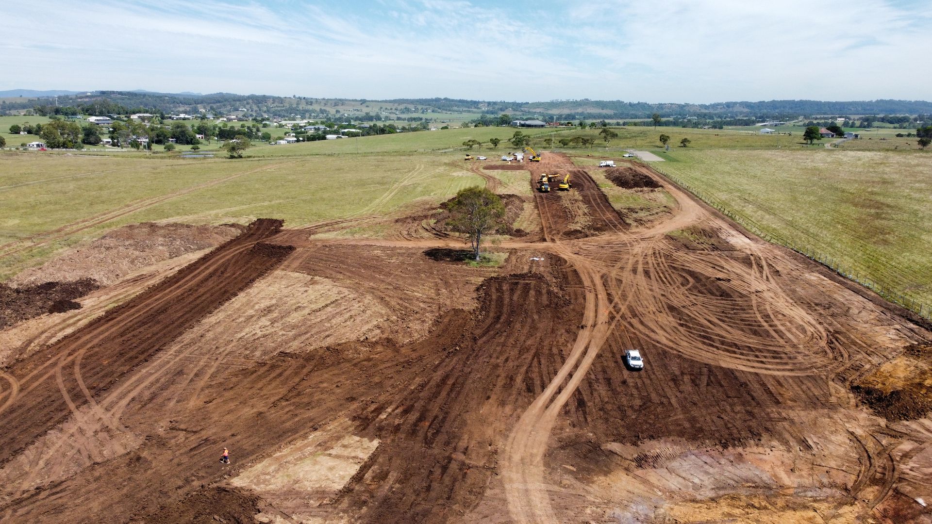 Aerial View of Construction Site Brown Earth and Dirt Roads Cutting Across Green Fields; Vehicles and Equipment Visible — Earthmoving in Maitland, NSW