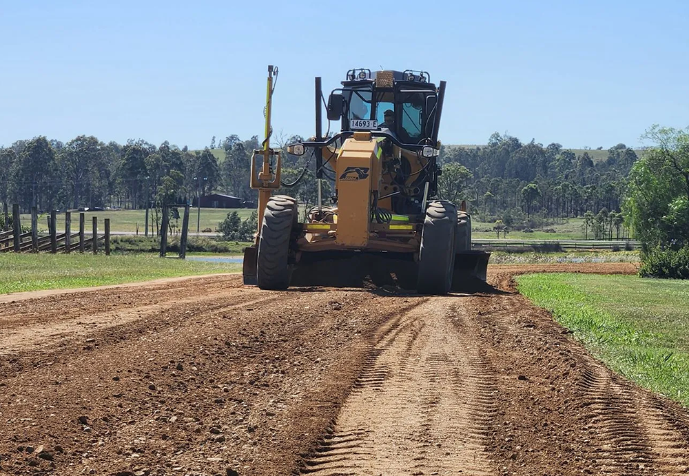 Yellow Grader Leveling Dirt on a Road