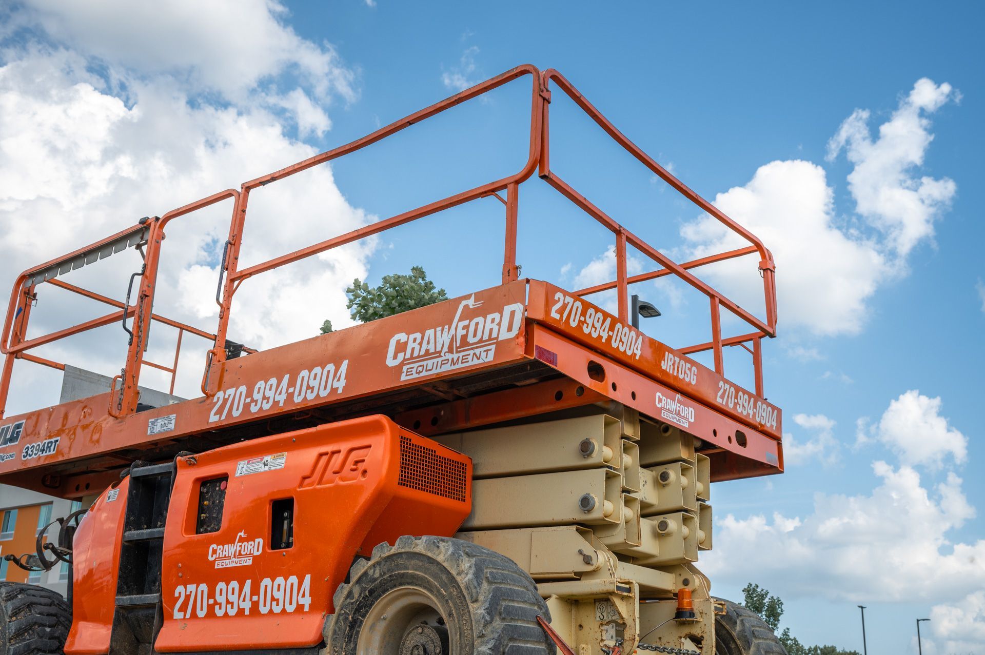 Orange construction lift with safety rails against a blue sky.