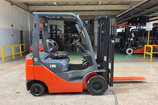 Orange and black forklifts parked in a row outside a warehouse.