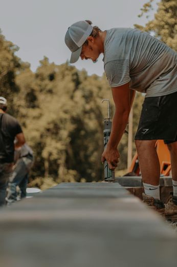 A man in a hat is working on a skateboard ramp.