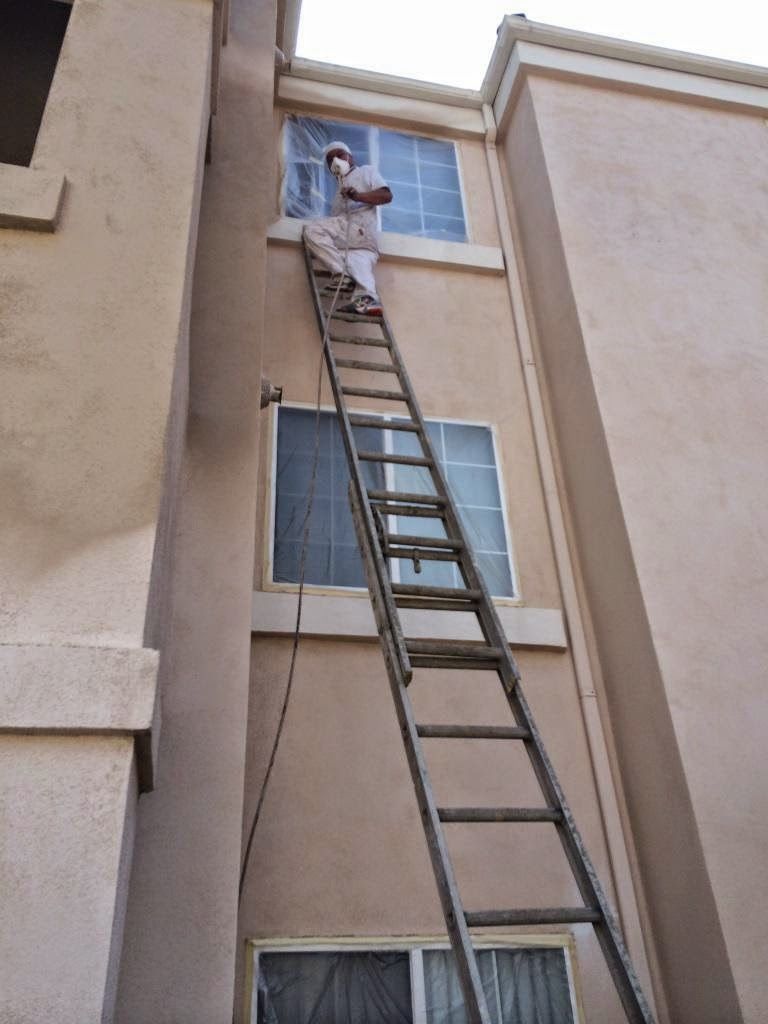 A man is painting the ceiling of a room with a paint roller.