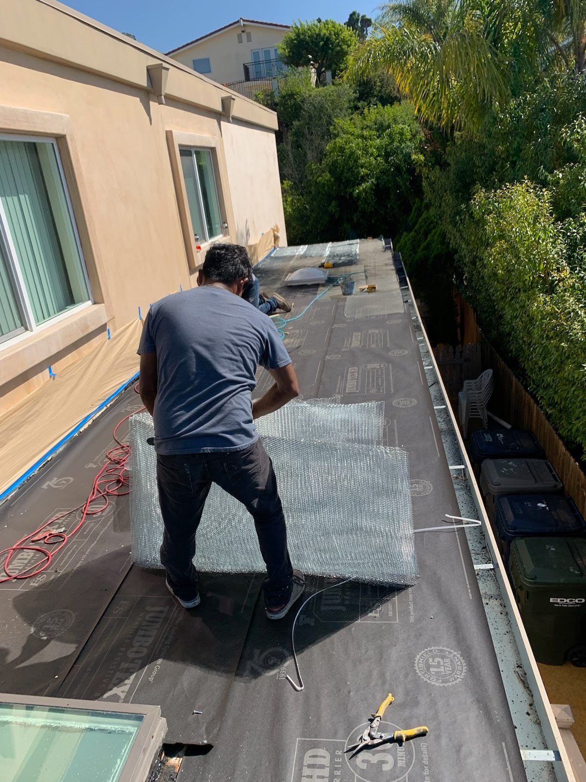A person is applying a roof sealant to a tile roof.