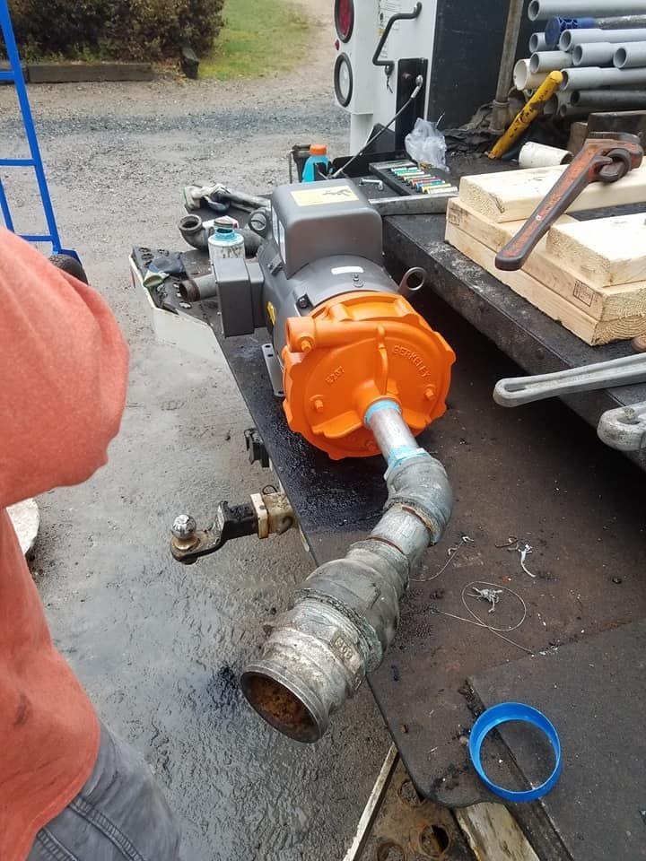 A person is standing next to a machine that is sitting on the back of a truck.