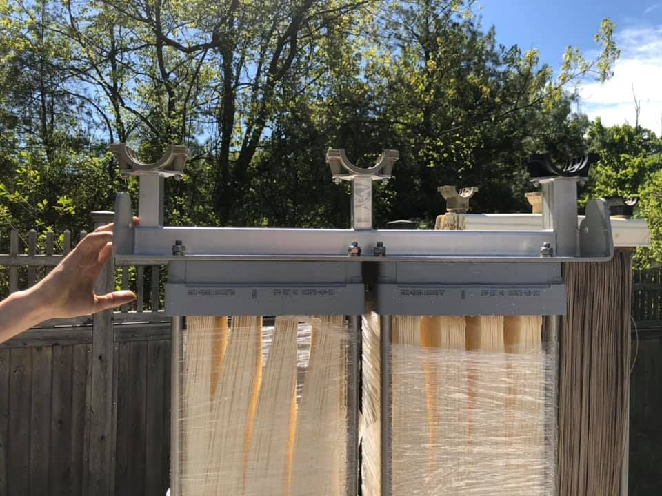 A person is standing in front of a fence holding a piece of metal.