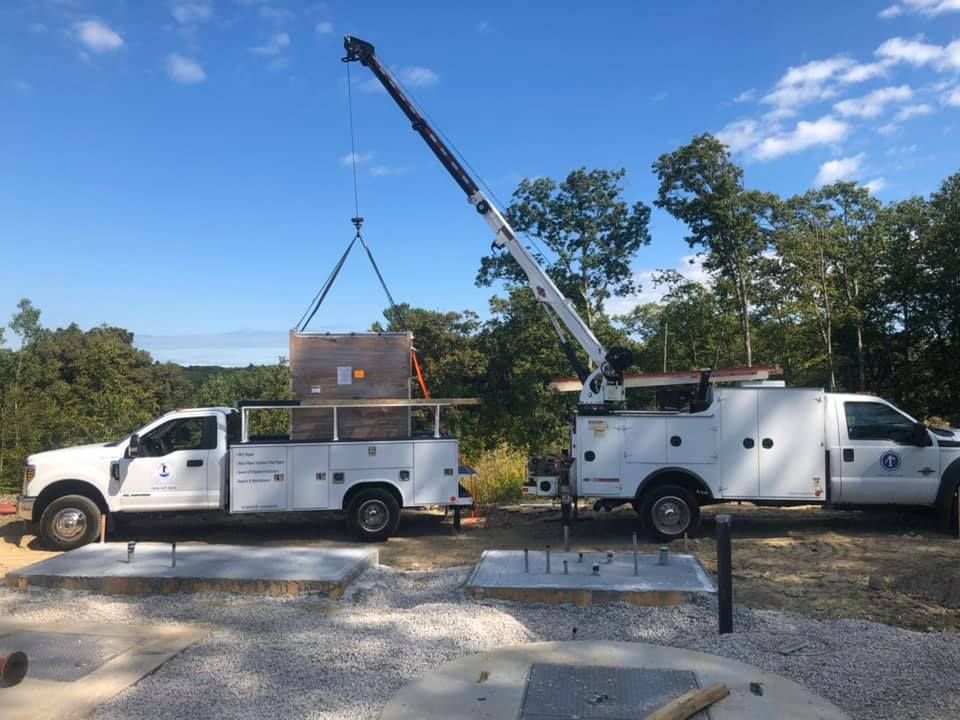 Two utility trucks are parked next to each other on a gravel road.