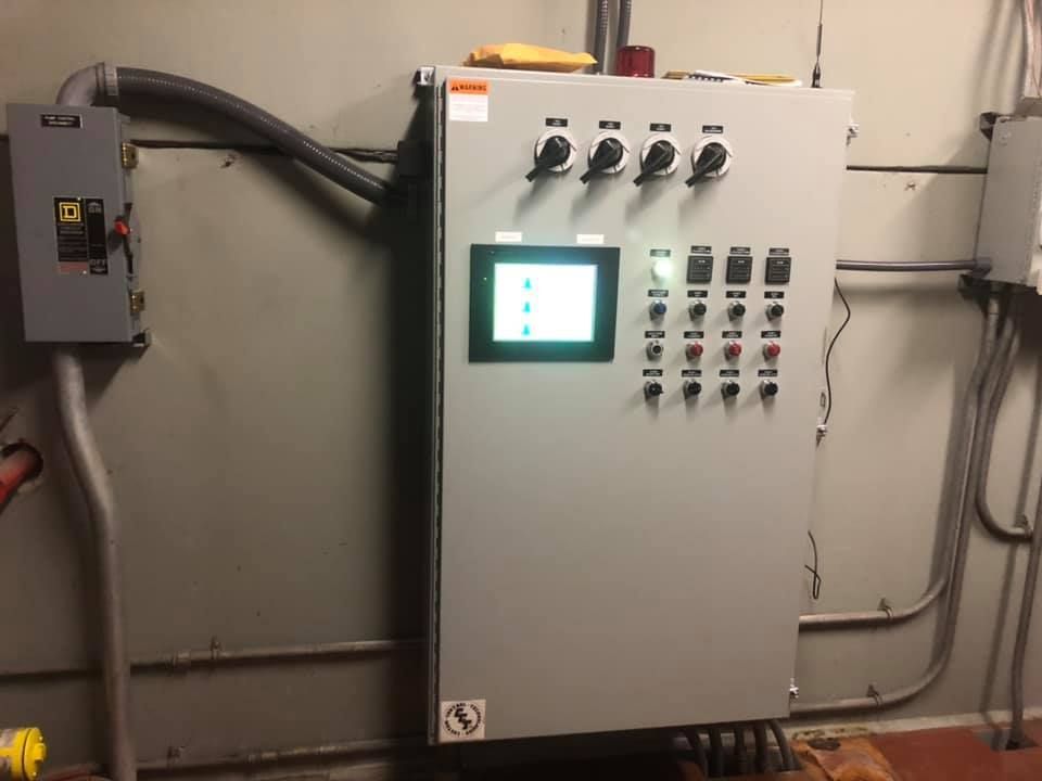 A control panel with a screen on it is hanging on a wall.