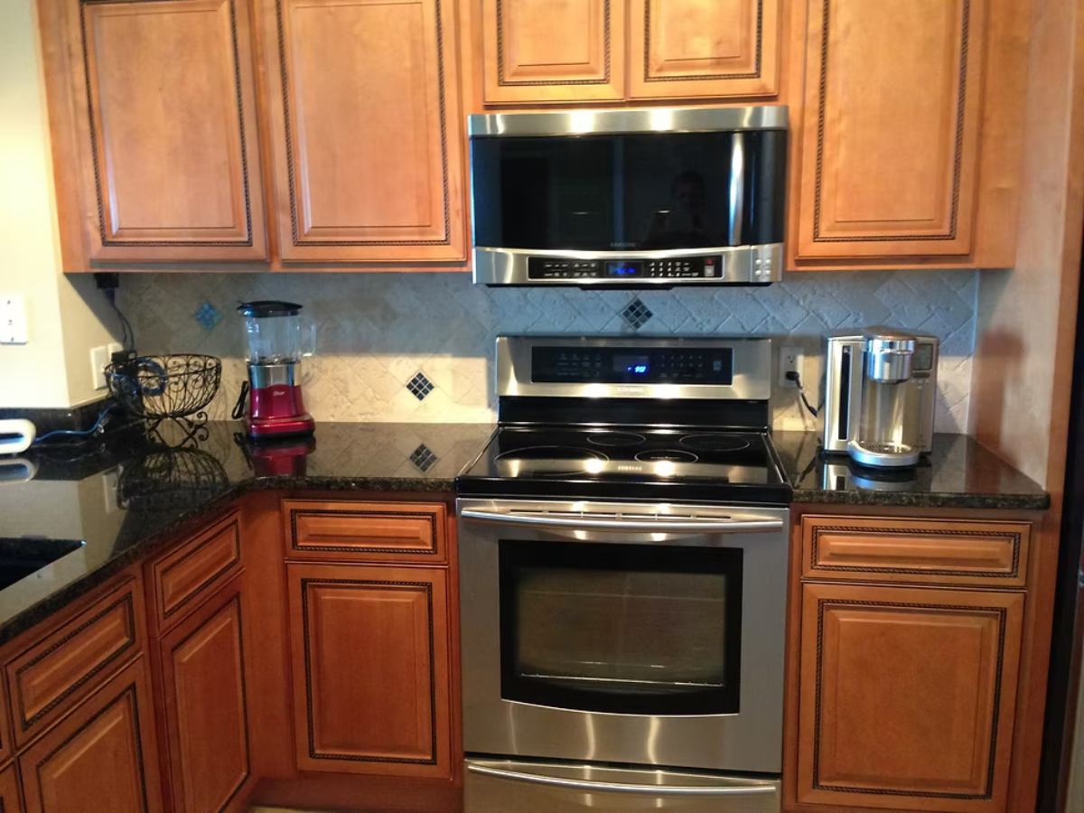 Kitchen with wooden cabinets, stainless steel appliances, and dark countertops.
