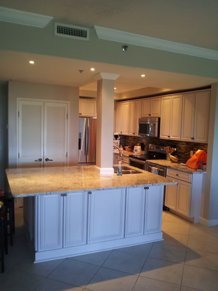 Kitchen with light gray cabinets, island with granite countertop, and stainless steel appliances.