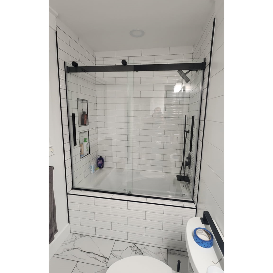 Bathroom with dual sinks, shower, and dark granite countertops.