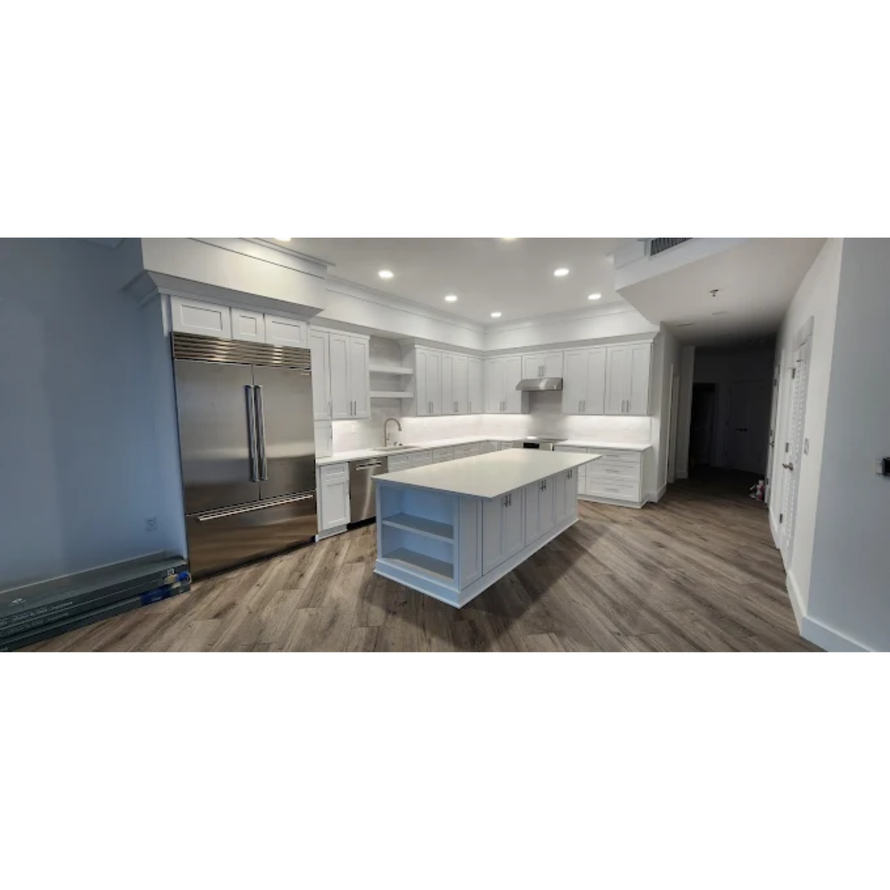 Kitchen with a granite countertop island, white cabinets, and wooden stools.