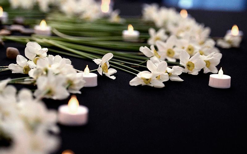 Flores blancas y velas sobre una superficie negra, creando una atmósfera pacífica y sombría.