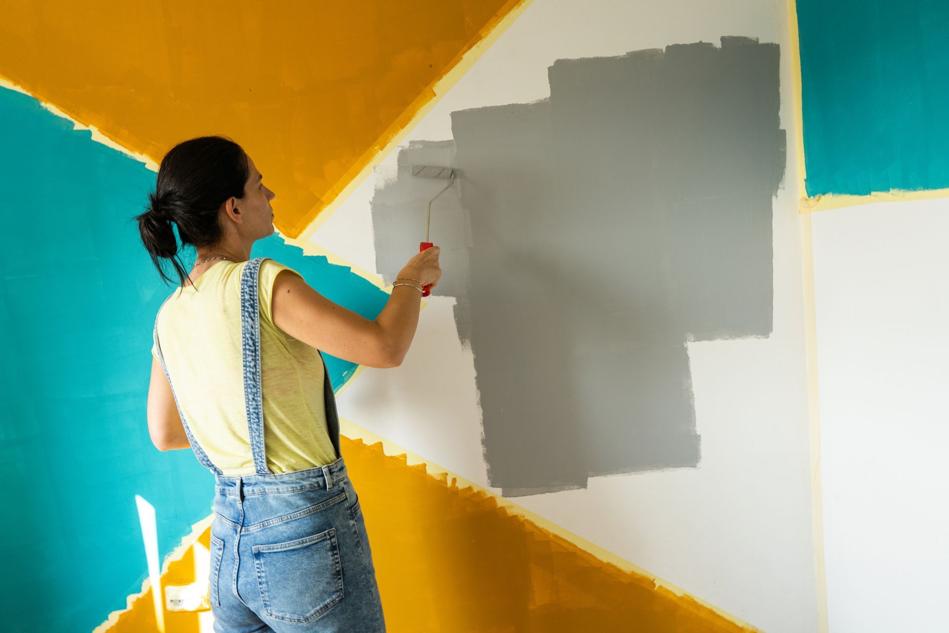 A woman is painting a wall with a paint roller.