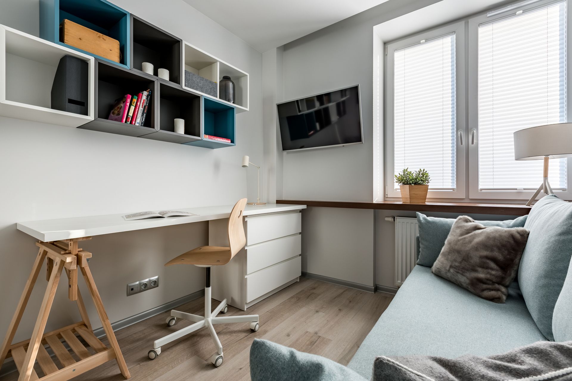 A living room with a couch , desk , chair and shelves.