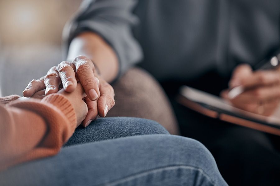 A person is holding another person 's hand while sitting on a couch.