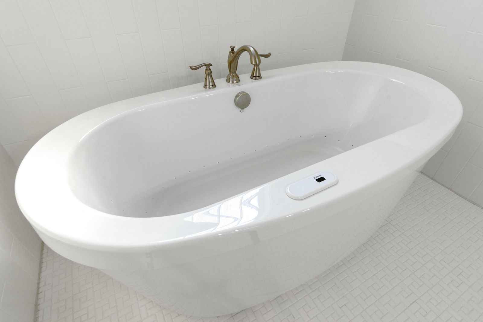 White oval bathtub with bronze fixtures in a bathroom.