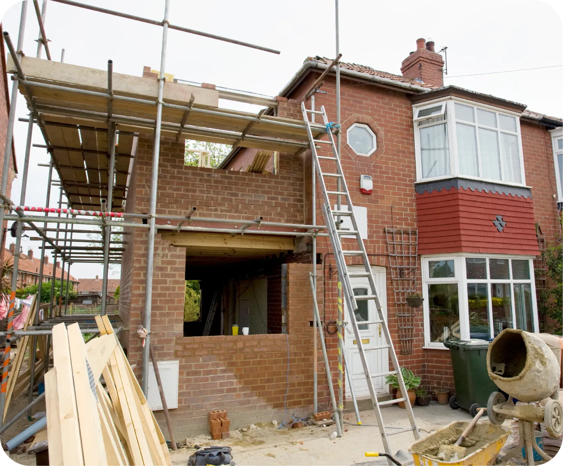 House exterior under construction, with scaffolding, brickwork, and a ladder.