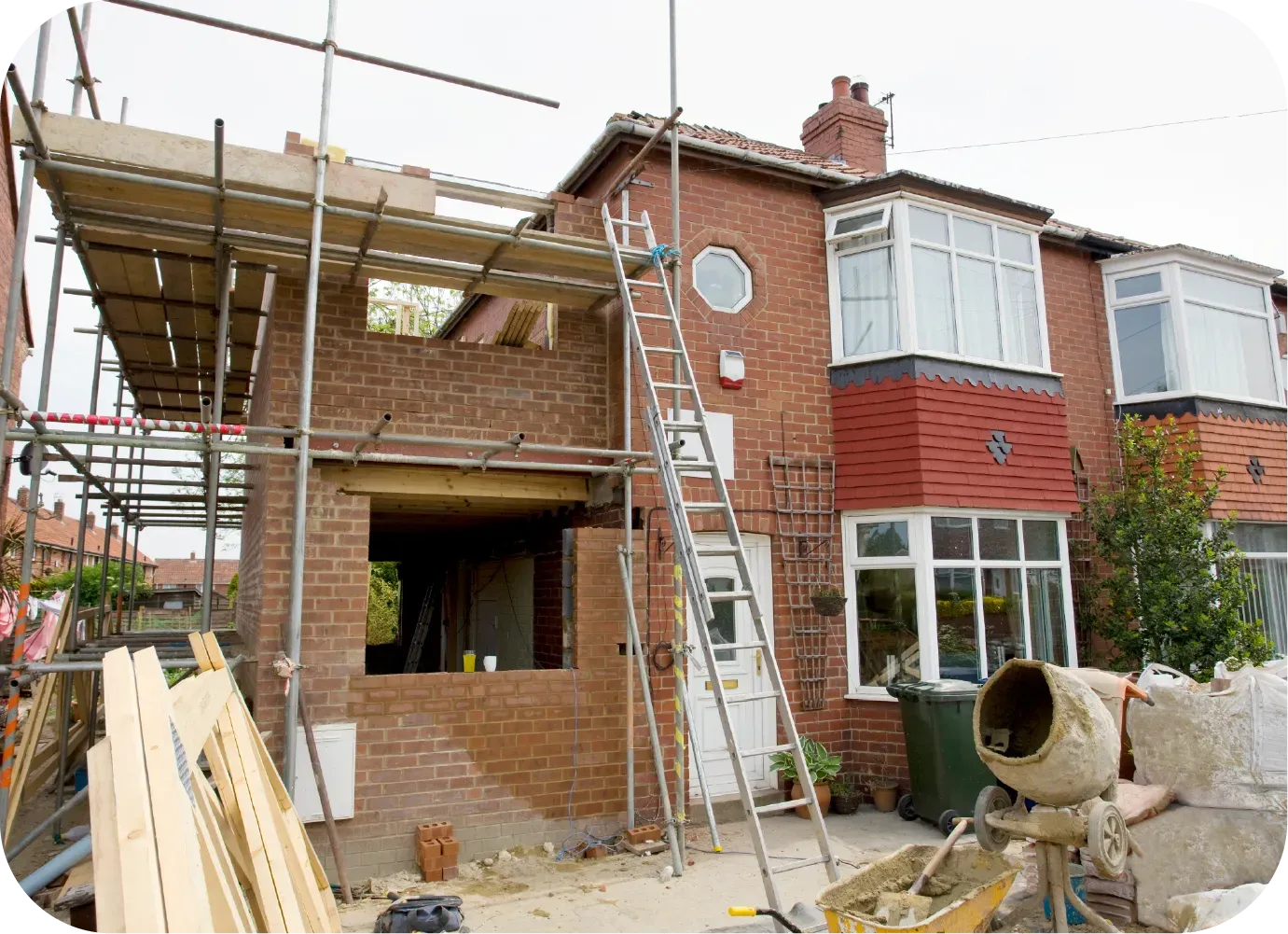 House under construction with scaffolding, a brick wall, and a ladder.