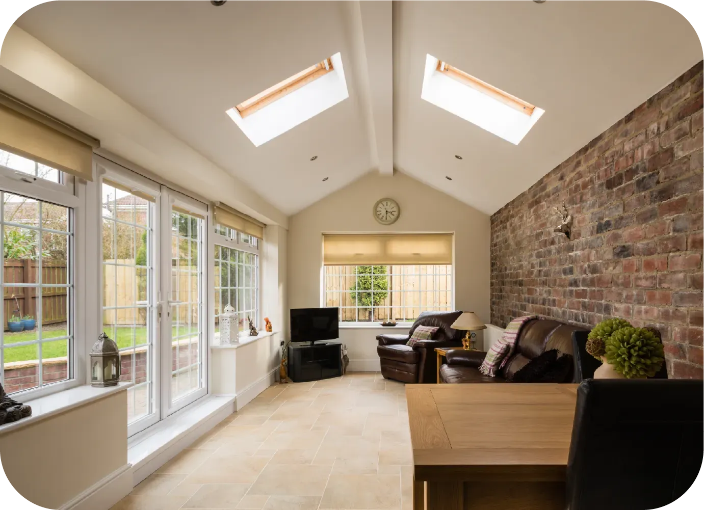 Sunroom with exposed brick wall, skylights, and windows overlooking a garden.