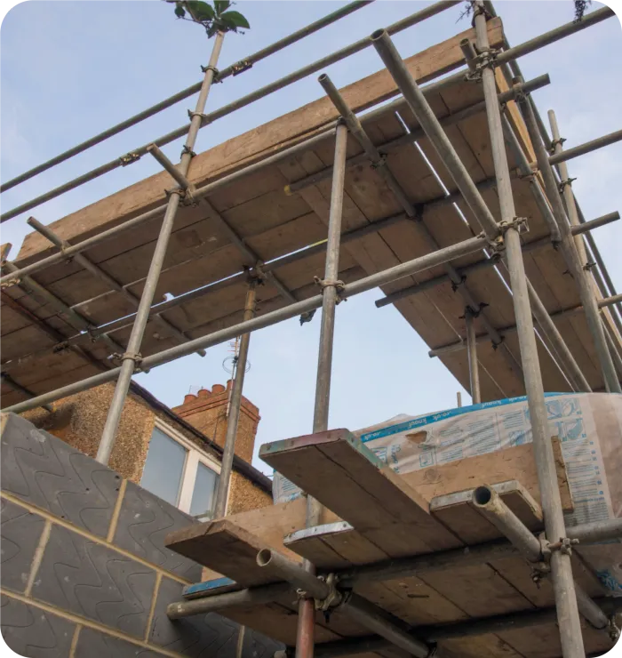 Scaffolding erected on a building under construction, with wooden platforms and metal supports.