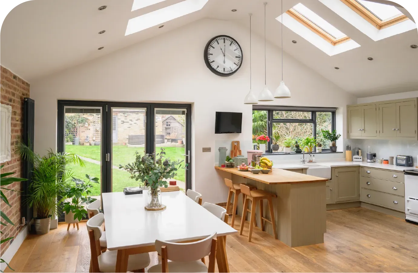 Kitchen and dining room with white vaulted ceiling, skylights, and wooden floor.