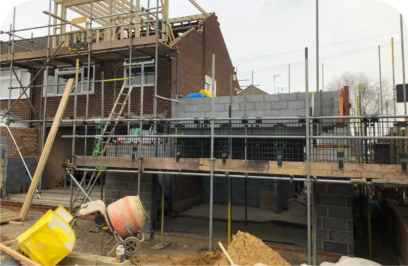 Construction site: house under renovation with scaffolding, bricks, and concrete blocks.