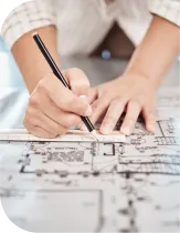 Person's hands using a pencil and ruler to draw on architectural blueprints.