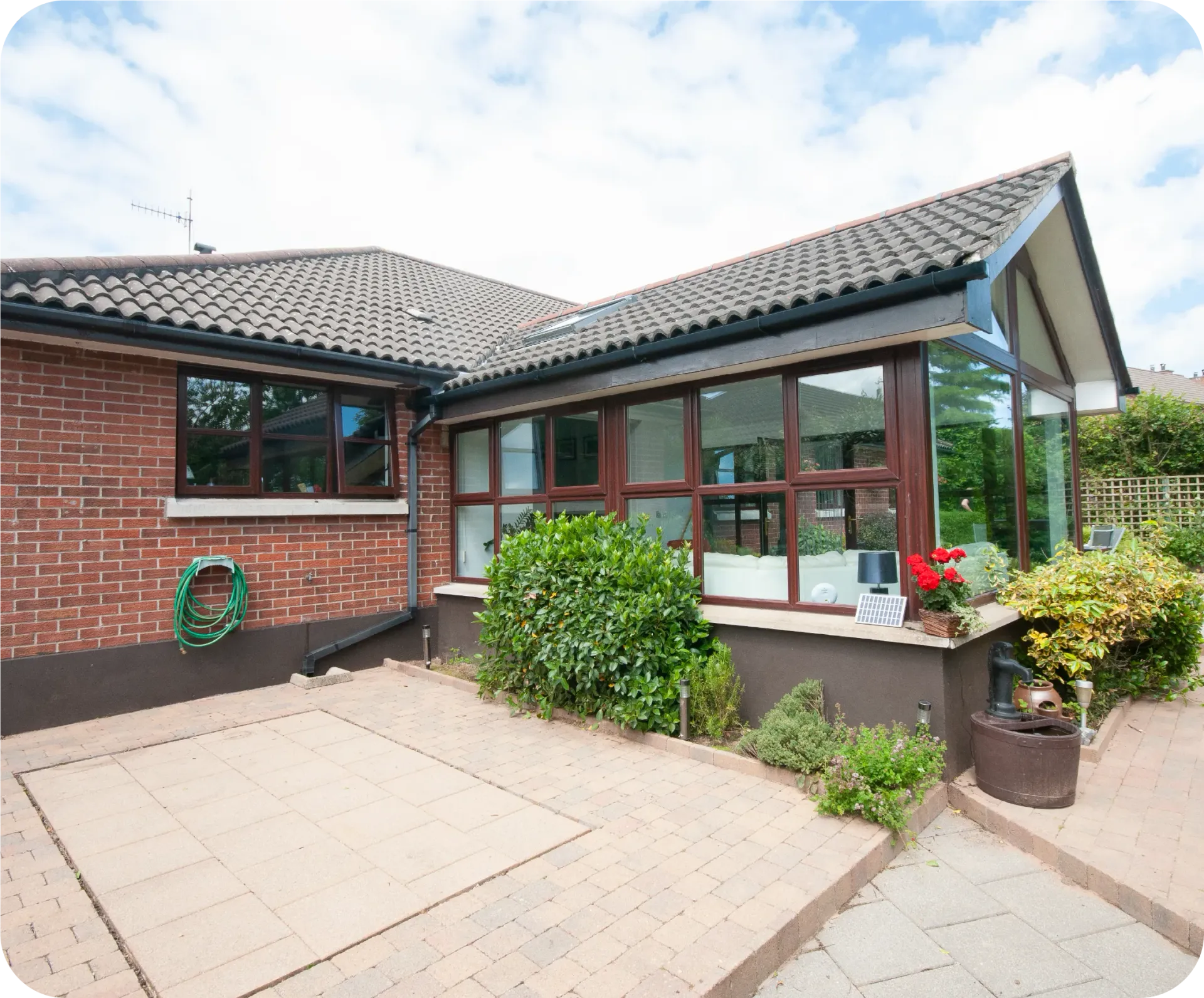 Brick house with large windows, patio, and garden.