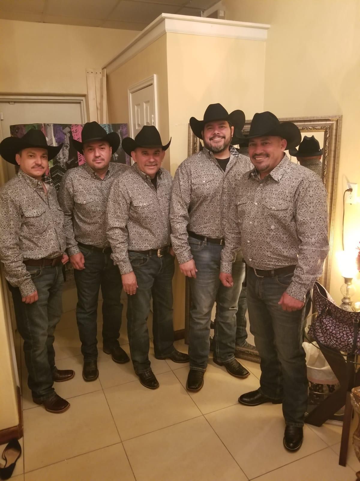 Grupo Orgullo wearing cowboy hats are standing next to each other in a room.