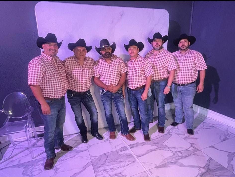 Grupo Orgullo wearing cowboy hats are standing next to each other in a room.