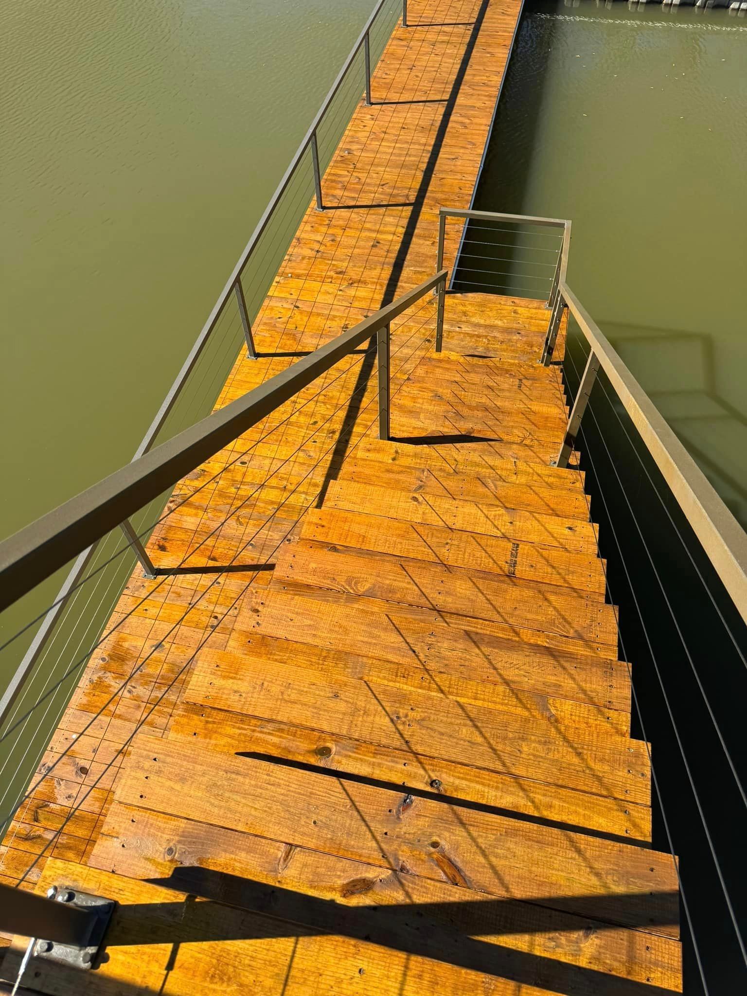 A wooden bridge over a body of water with stairs leading up to it.