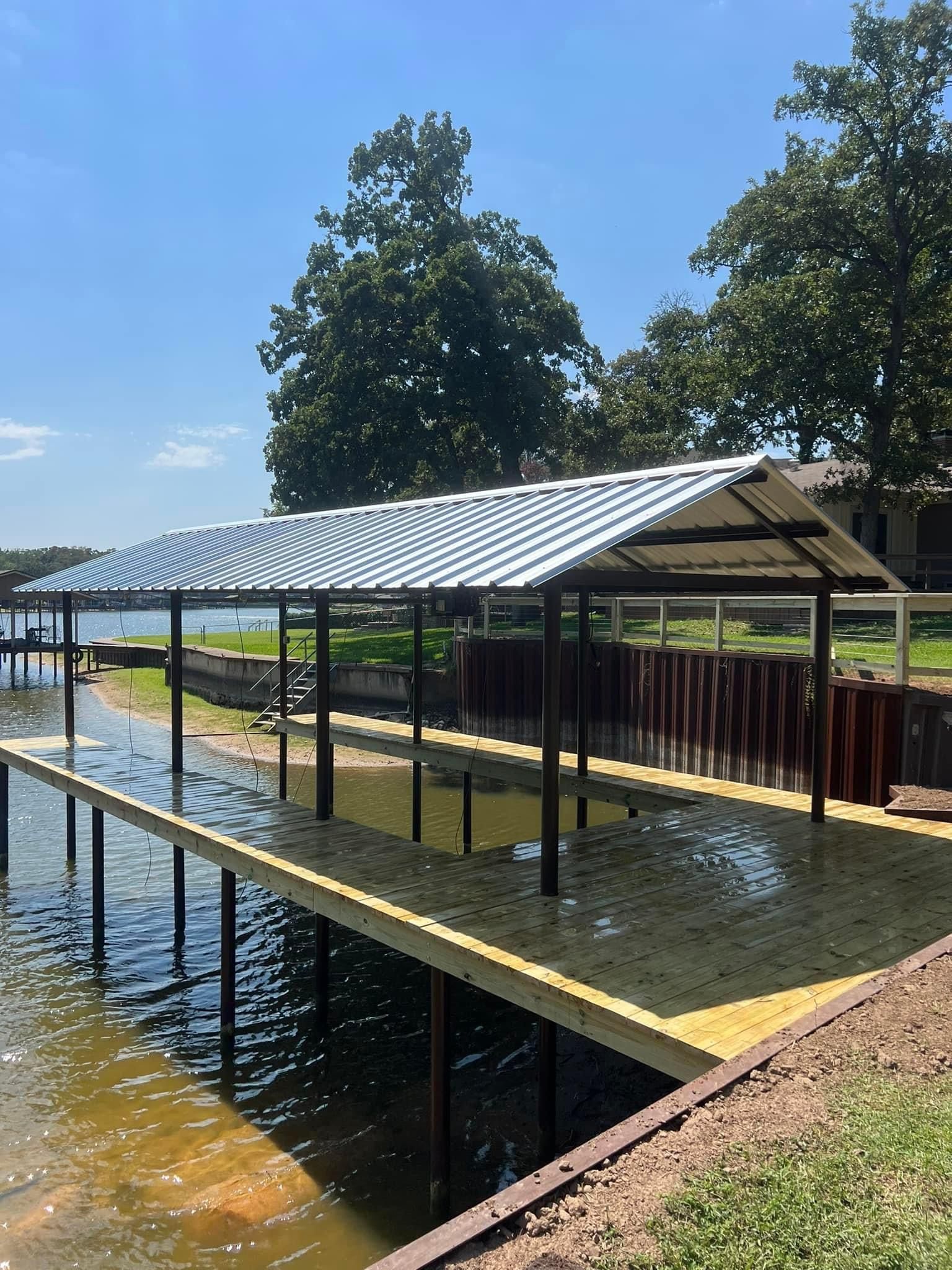 A dock with a canopy over it is next to a body of water.