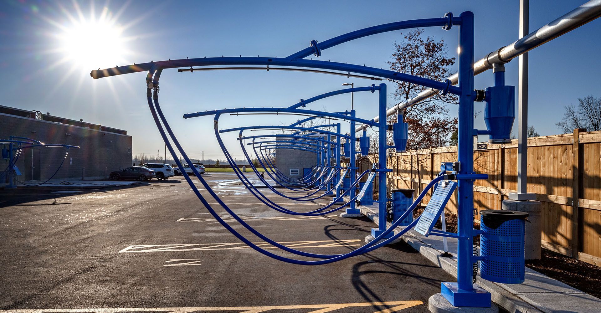 A row of blue pipes are lined up in a parking lot.
