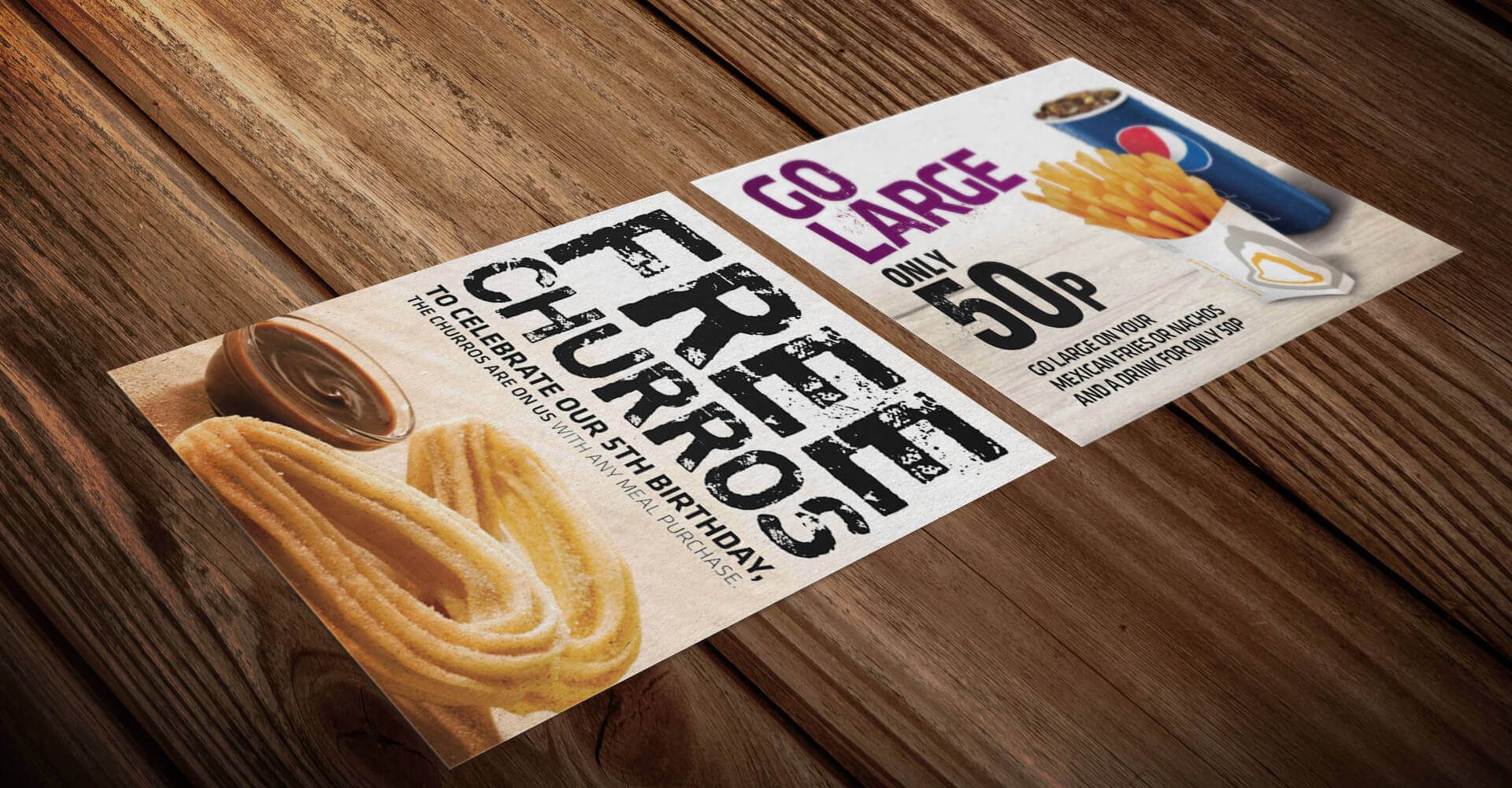 Two flyers for churros are sitting on a wooden table.