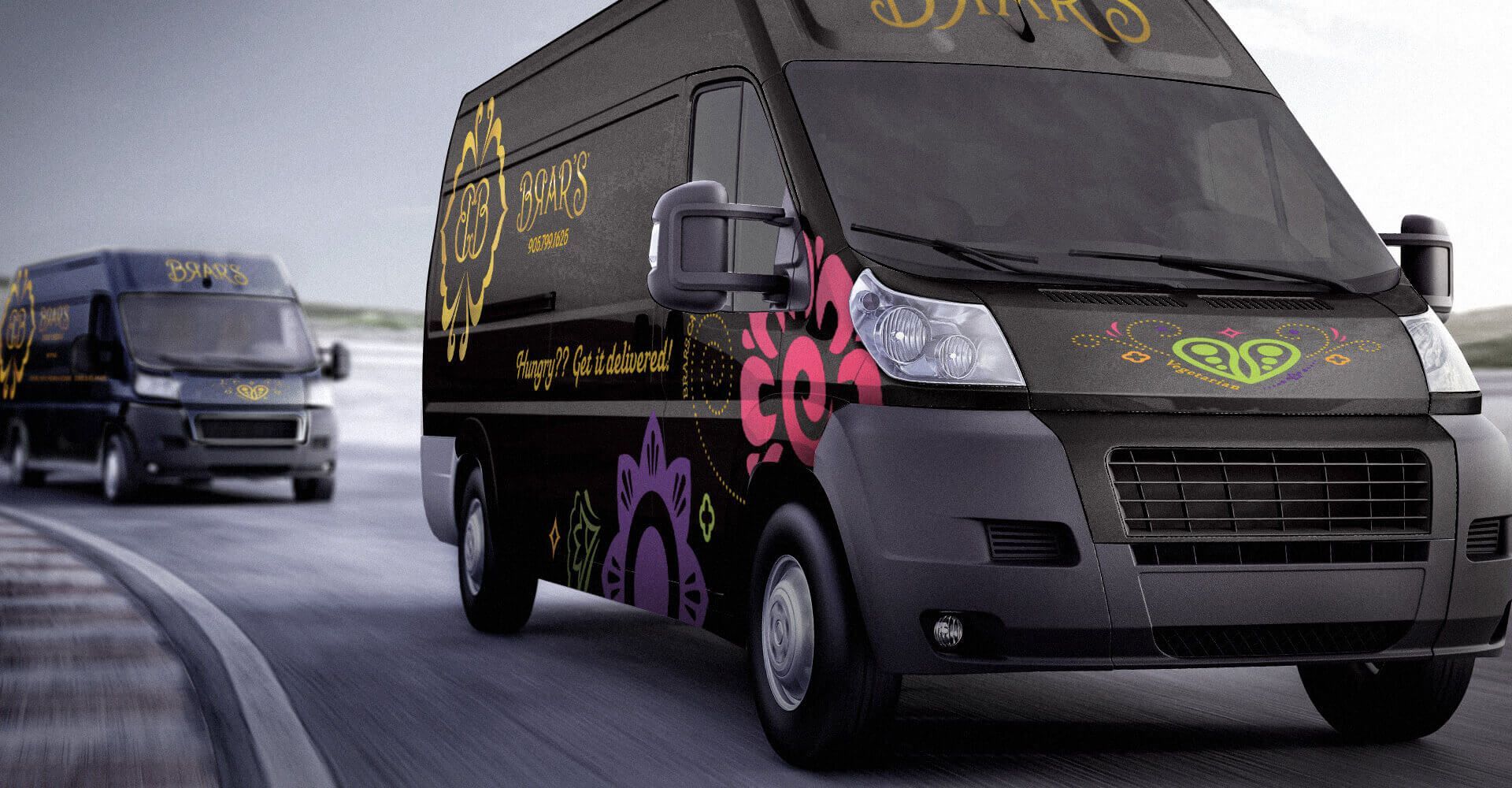 Two black vans are driving down a road