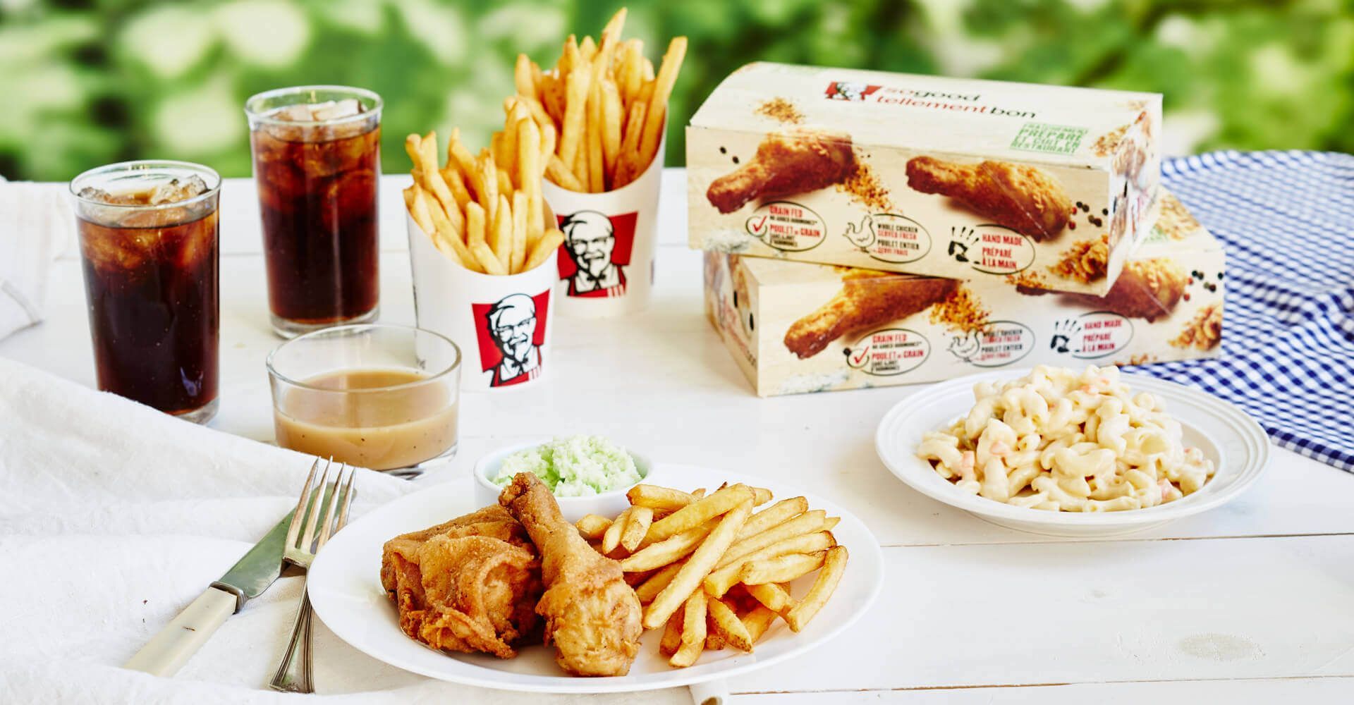 A table topped with plates of fried chicken , french fries , and macaroni and cheese.