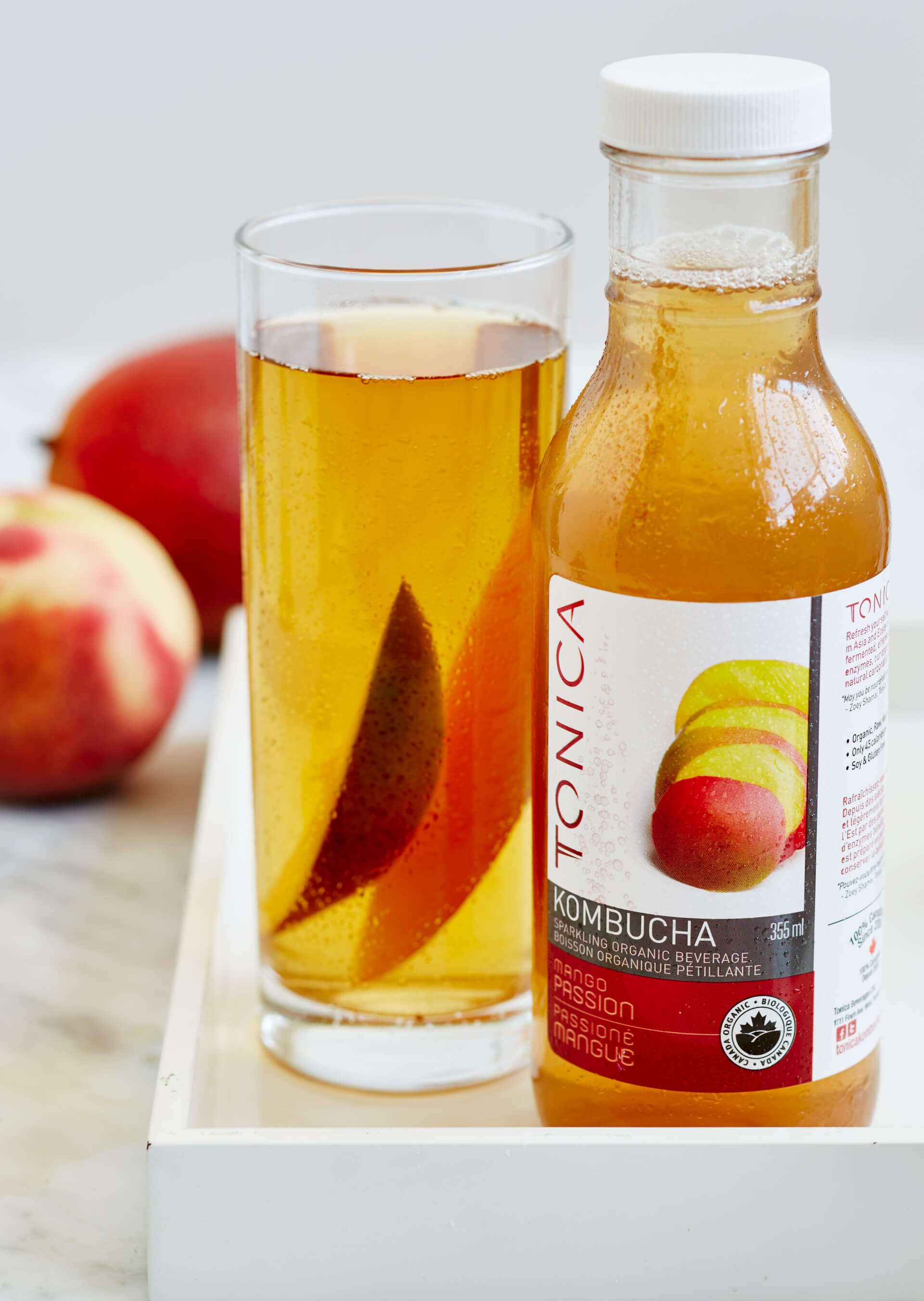 A bottle of kombucha next to a glass of kombucha