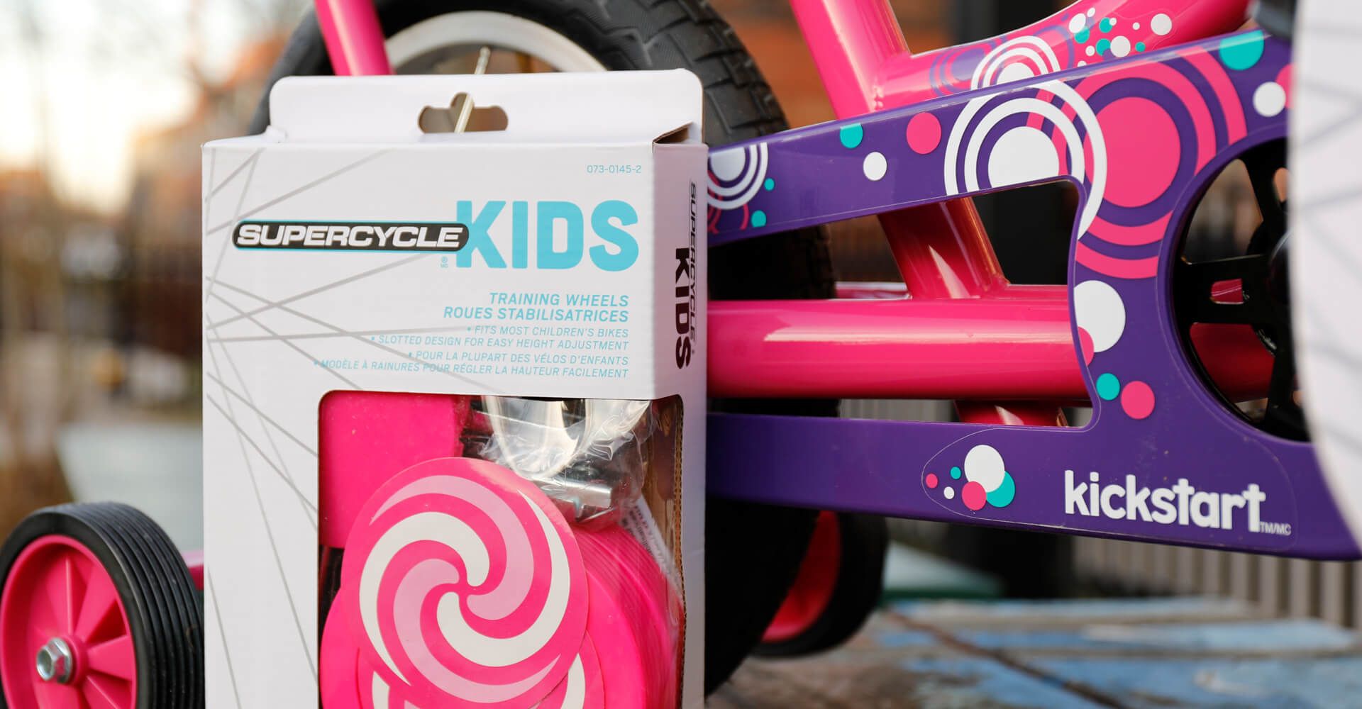 A pink and purple bicycle with a box that says kids on it