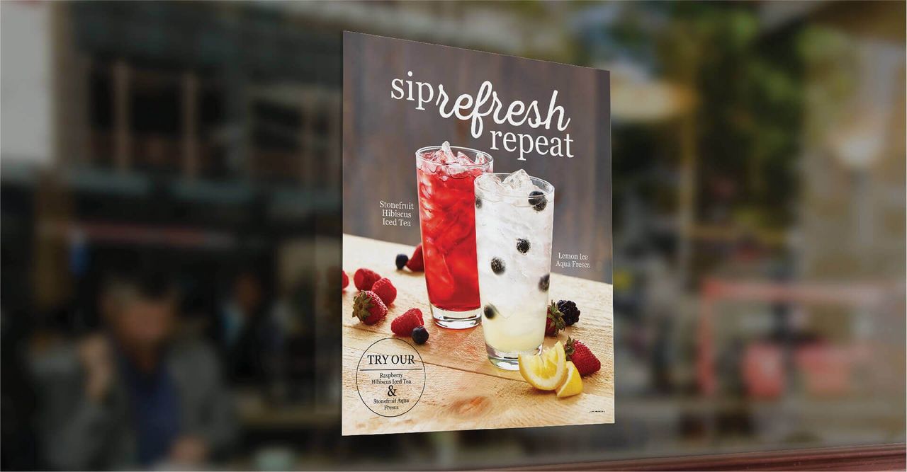 A poster of two drinks is hanging on a window.