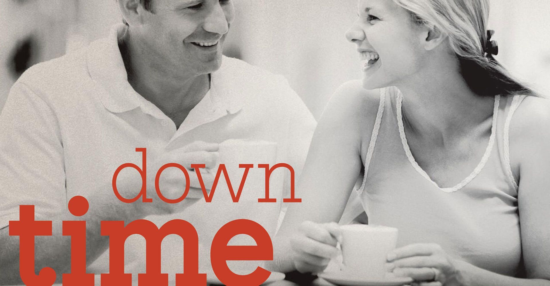 A man and a woman are sitting at a table with the words down time above them
